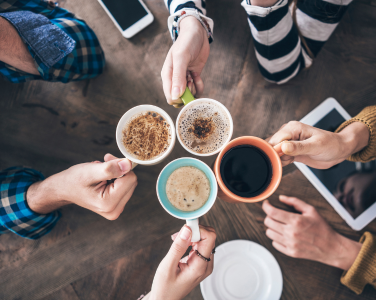 Les mains de quatre personnes tenant des tasses de café.