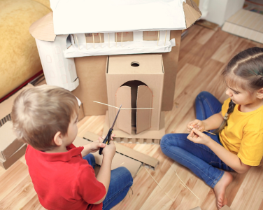 Deux enfants en train de construire un fort en carton. 
