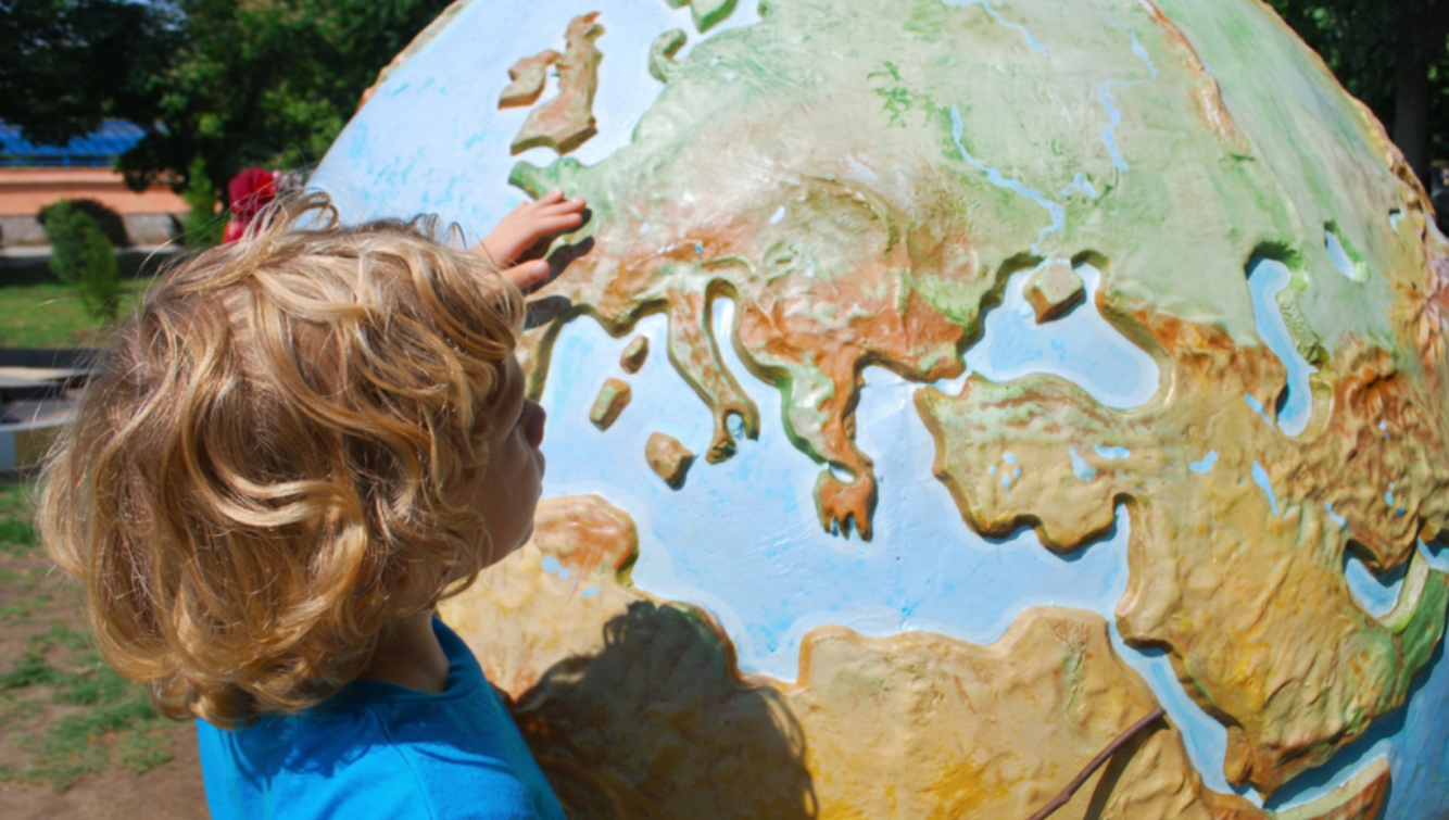 Un enfant qui explore un globe terrestre coloré.