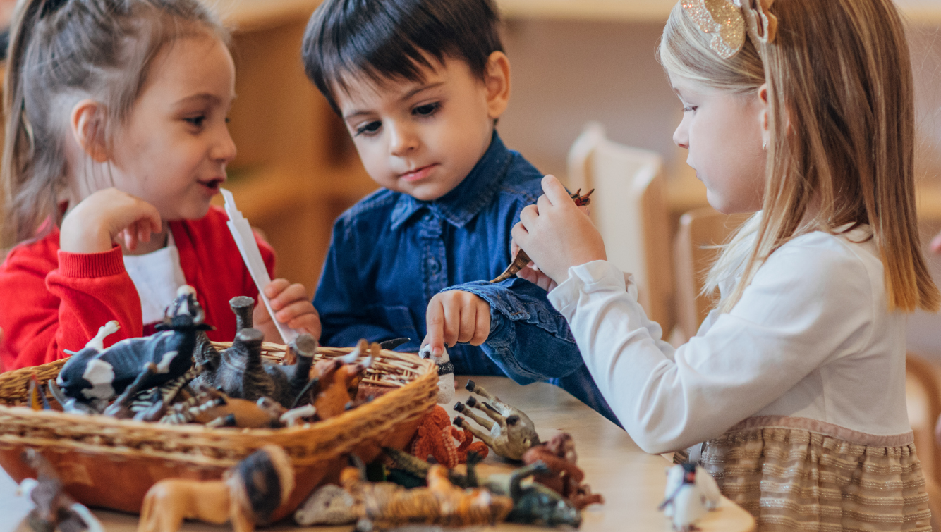 Des enfants jouent autour d'une table avec des jouets d'animaux.