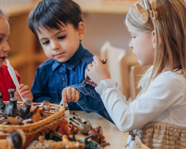 Des enfants jouent autour d'une table avec des jouets d'animaux.