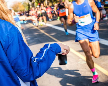 Volunteer handing water to runner during race.
