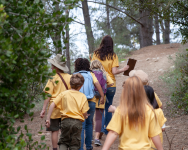 Groupe d'enfants et d'un adulte marchant sur un sentier forestier.