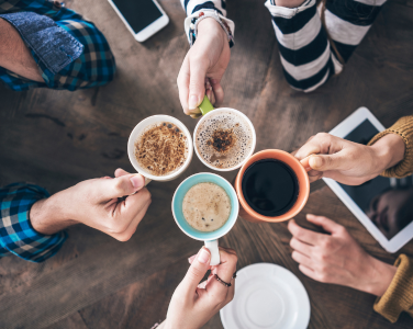 Quatre mains tenant des tasses à café dans un toast