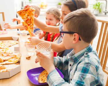 Des enfants mangent une pizza autour d'une table.
