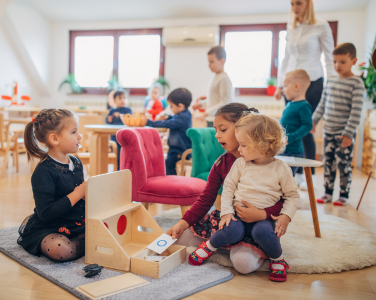 Enfants jouant avec des jouets dans une salle de classe lumineuse.