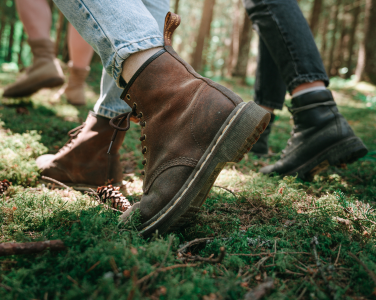 Gros plan sur des bottes marchant sur un sol forestier recouvert de mousse.