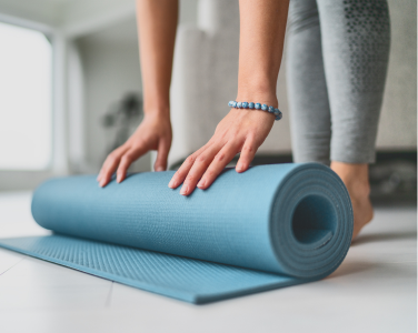 Personne déroulant un tapis de yoga sur le sol