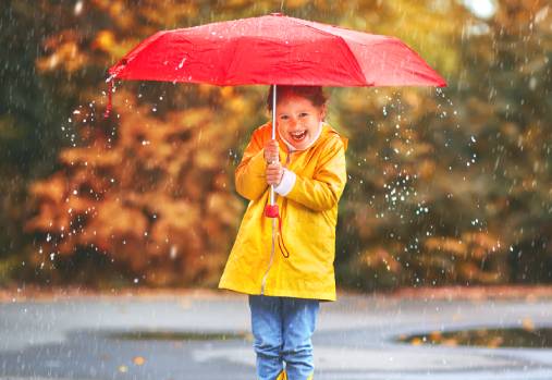 jeune enfant qui joue dans la pluie avec un parapluie rouge