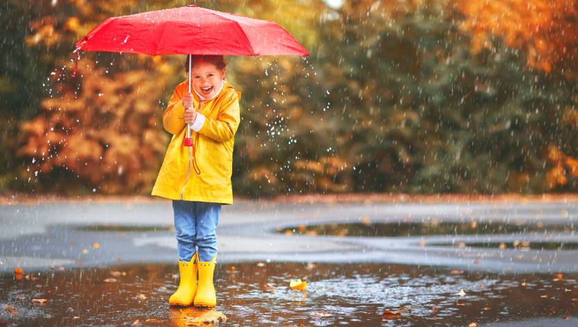 petite fille debout sous la pluie avec un parapluie