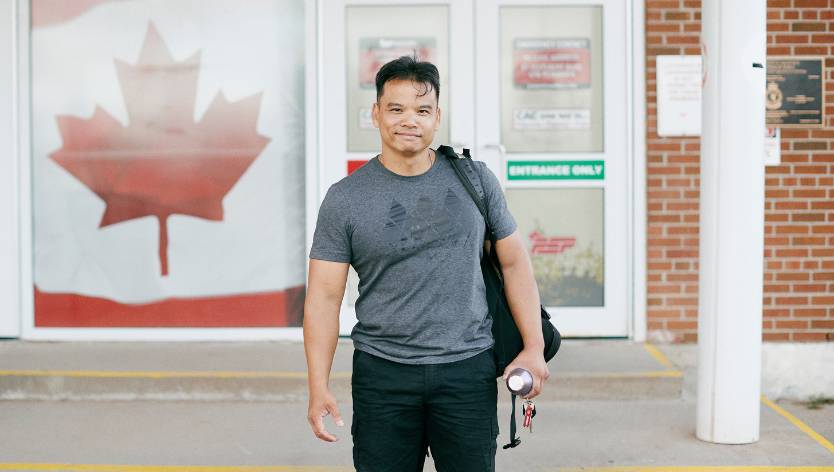 Membre des FAC souriant et debout en face des installations de conditionnement physique