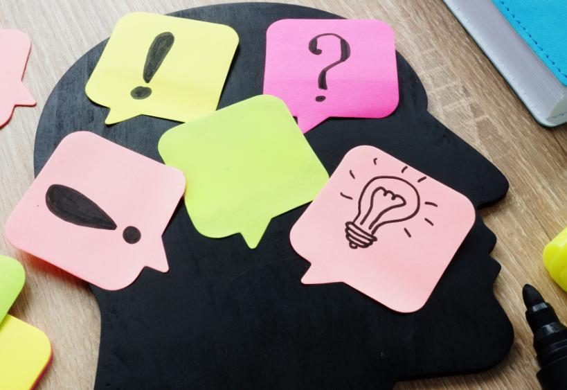 Silhouette de tête avec des notes autocollantes représentant une ampoule et des points d’exclamation.