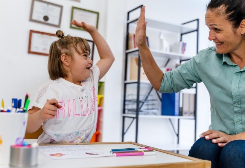 enseignante et petite fille ayant le syndrome de Down qui se tapent dans la main