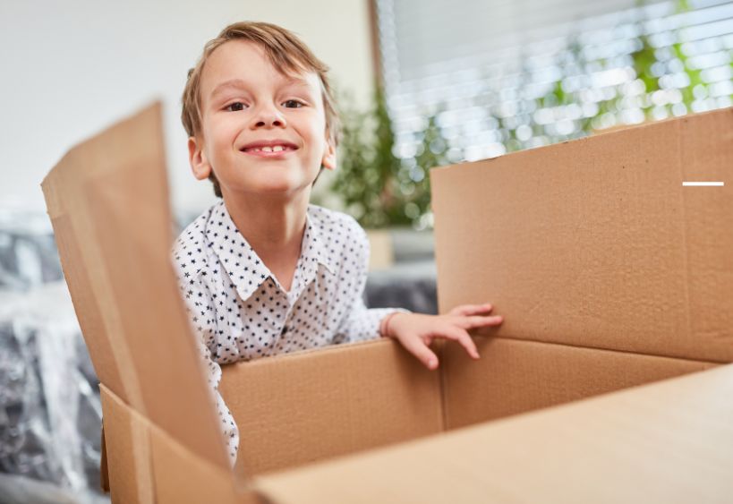 garçon penché sur une boîte en carton, souriant