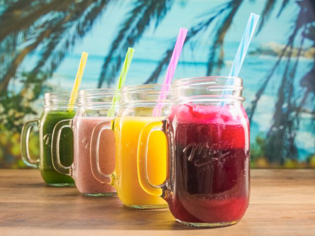 Des smoothies aux couleurs vives servis dans des bocaux Mason avec des pailles colorées, parfaits pour se rafraîchir en été.