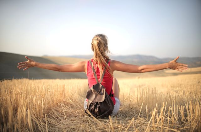 Femme profitant du grand air et d’un sentiment de liberté, assise dans un champ de foin au coucher du soleil.
