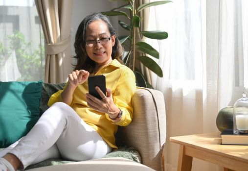 femme assise sur un canapé regardant son téléphone 