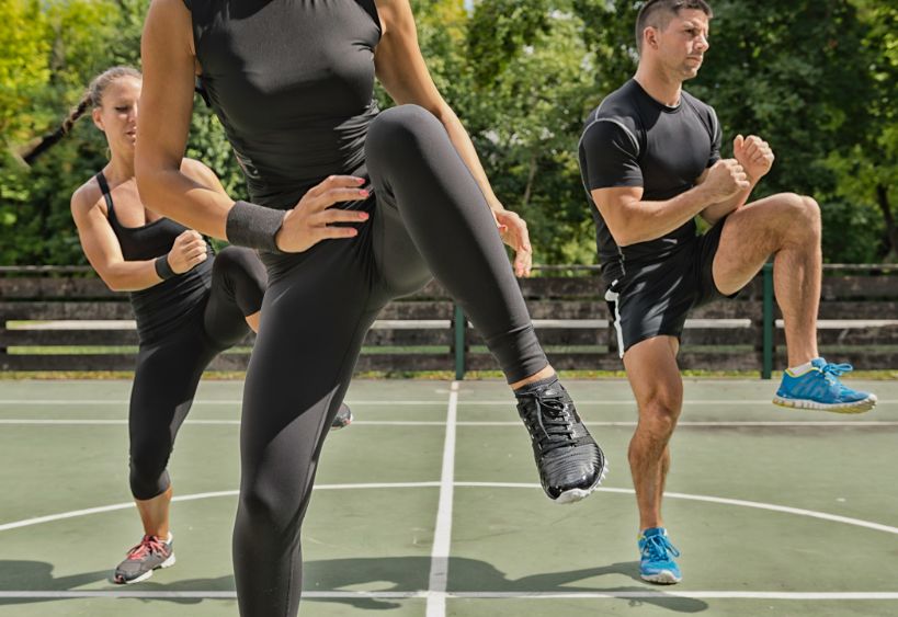 Trois personnes participent à une séance d'exercices physiques en plein air.