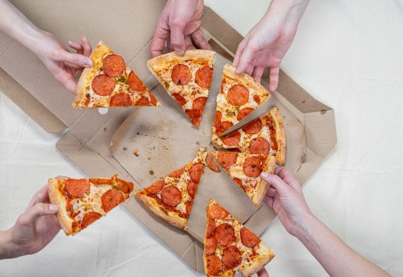 des mains qui tiennent des morceaux de pizza