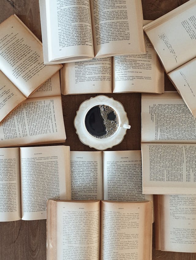 Disposition à plat de livres ouverts entourant une tasse de café, créant une ambiance de lecture relaxante.