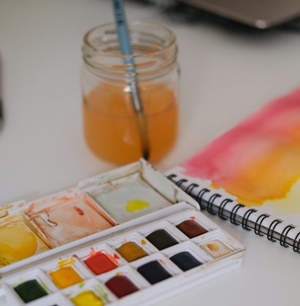  table blanche avec une palette d’aquarelle et un livre d’aquarelle ouvert 