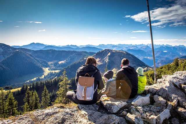 dos d'une famille assise au sommet d'une montagne