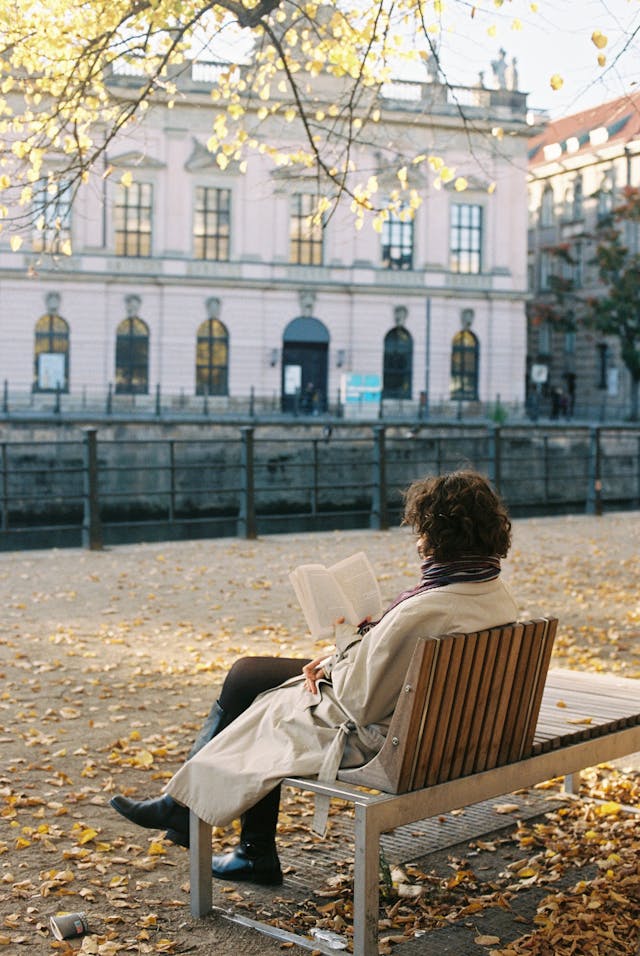 Femme se relaxant sur un banc public en lisant un livre