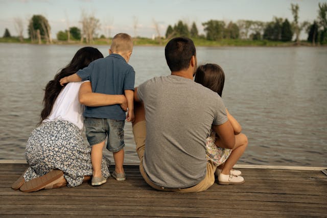 Vue de dos d'une famille assise au bord de la rivière