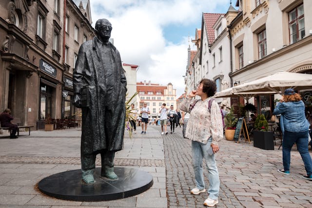 Une femme debout à côté d'une statue représentant un homme
