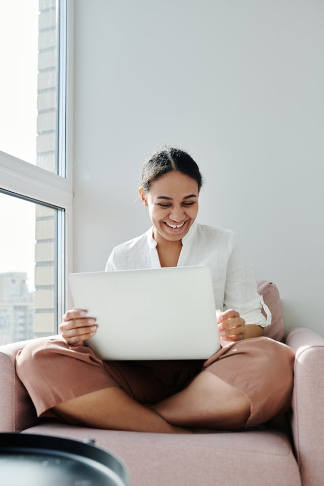femme regardant et souriant un ordinateur portable