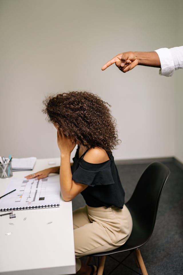 Il pointe du doigt une femme assise sur une chaise alors qu'il examine un dossier