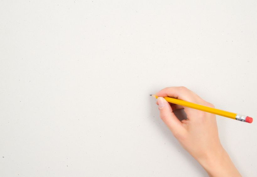 Main tenant un crayon, dessinant sur du papier blanc.