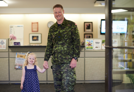 Un militaire en uniforme tenant la main de sa fille