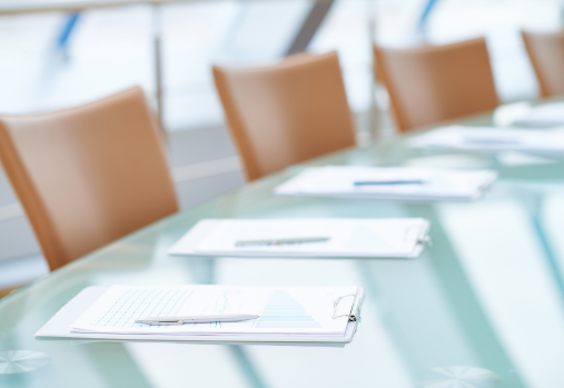 une table de salle de réunion sur laquelle sont disposés les rapports de l'assemblée générale annuelle, avec un stylo à chaque place