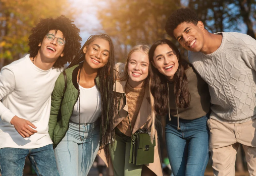 un groupe d'ados qui sourient à la caméra devant des arbres aux couleurs de l'automne