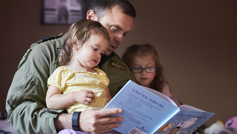 father reading a book with two children