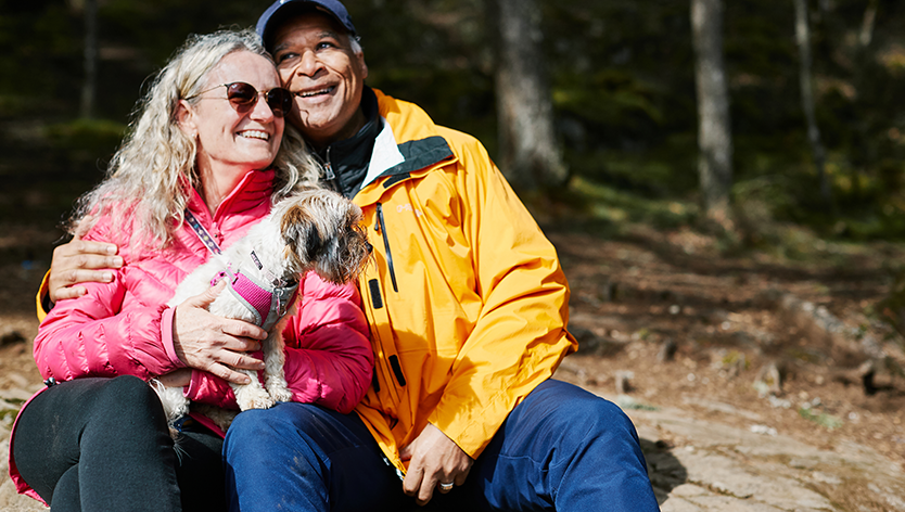 retired couple sitting in woods with dog