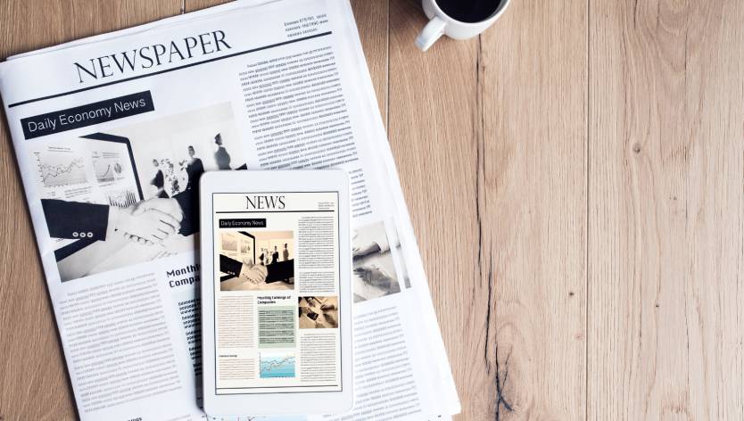 une tablette, un journal et une tasse de café