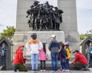 enfants et membres de l'armée au pied de la statue commémorative