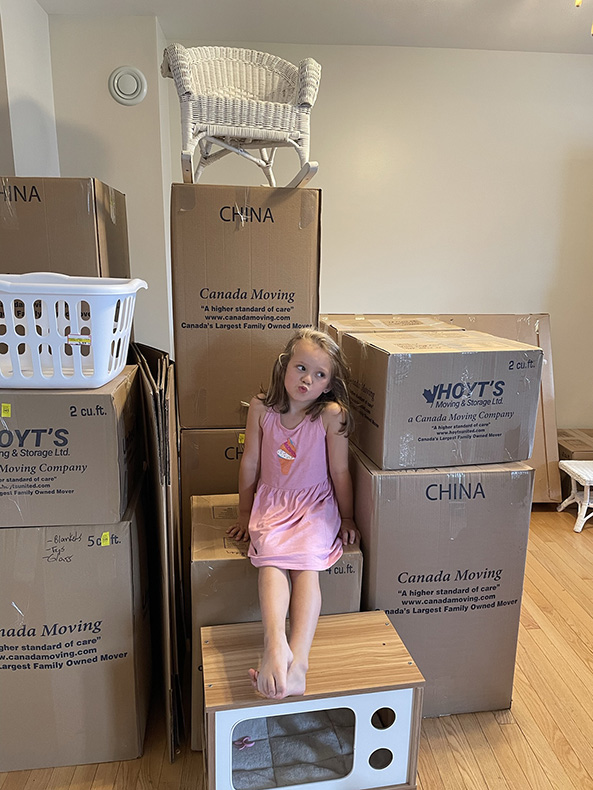 little girl sitting on moving boxes