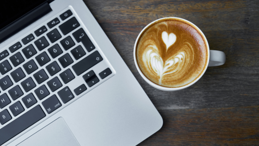 trois mains tenant des tasse de café a côté d'un laptop