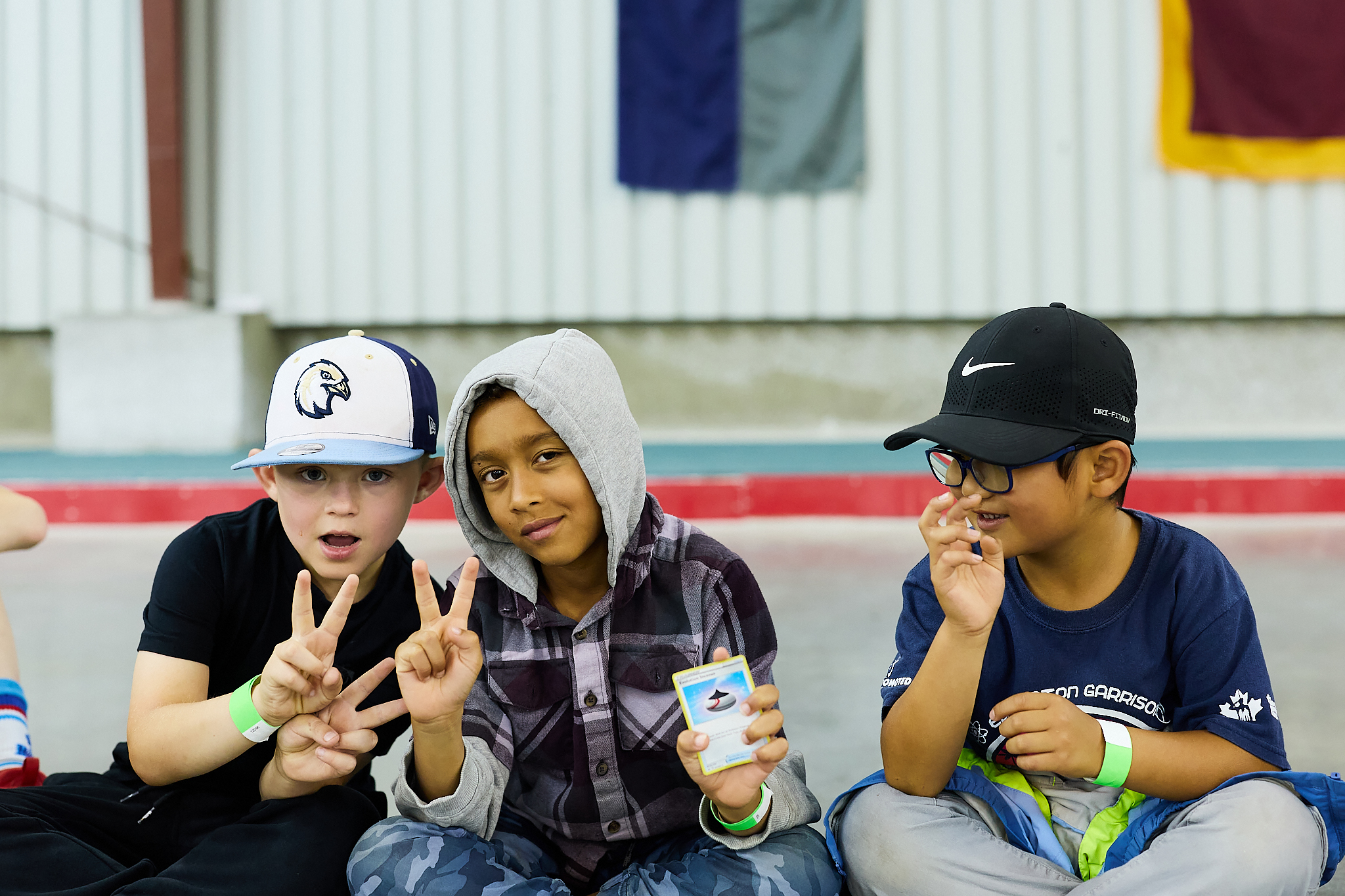 Trois enfants d’âge scolaire, souriant de façon détendue à l’appareil photo, tiennent une carte Pokémon.