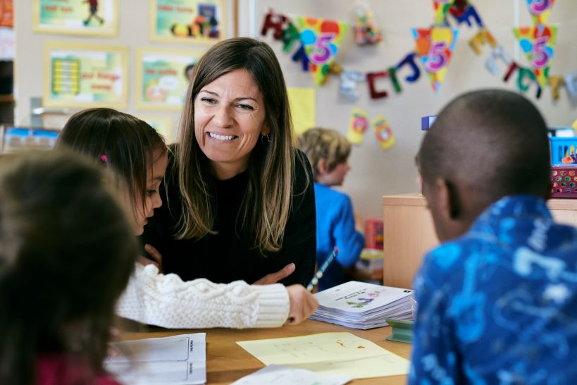 Enseignante et étudiants souriant et assis autour d'une table