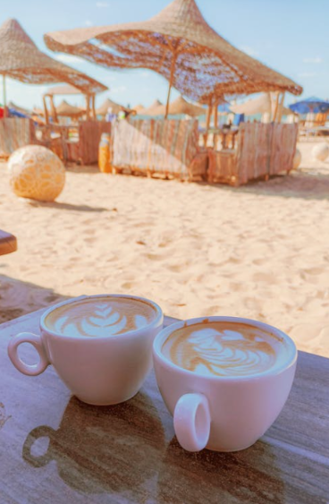 Deux tasses de café posées sur une table à côté d'une plage de sable