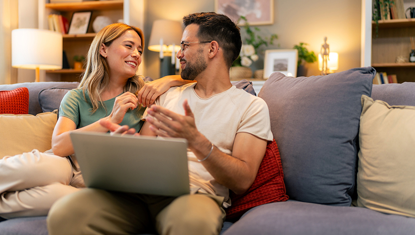 Couple qui discute sur un sofa avec un ordinateur