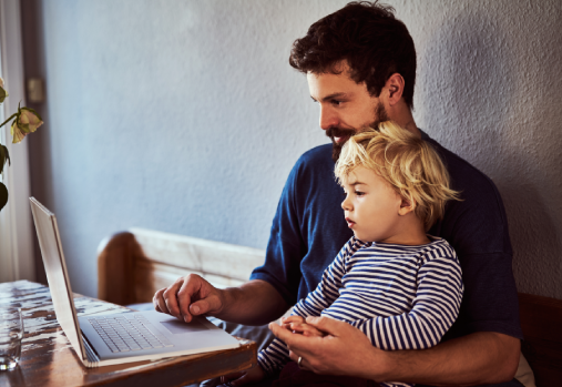 homme sur son ordinateur avec un enfant dans ses bras